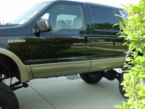 2001 Ford Excursion - Black and tan Ford Excursion shown from the side, with "EXCURSION" badging visible.