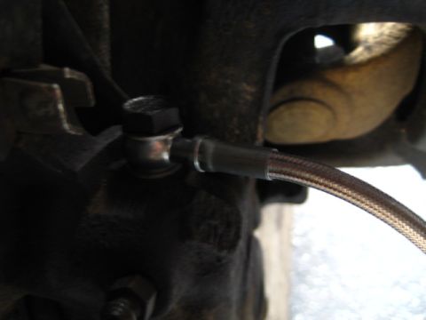 1989 Ford Bronco - Detail of a braided brake line connection, with a Supermotors.net watermark in the corner.