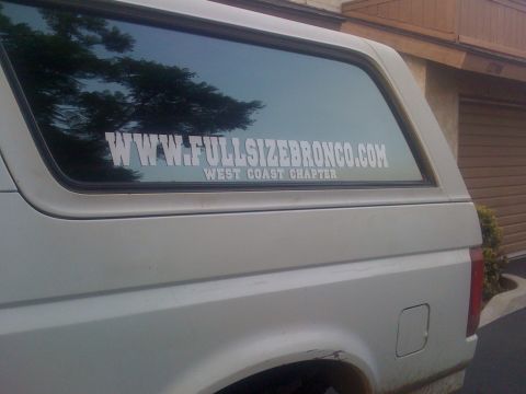 1995 Ford Bronco - A white SUV is seen from the side, a large sticker on its rear window that reads WWW.FULLSIZEBRONCO.COM WEST COAST CHAPTER.