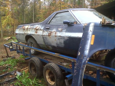 1973 Ford Ranchero - A weathered blue Ford Ranchero sits on a trailer, showing signs of rust and disrepair.