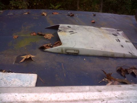 1973 Ford Ranchero - A weathered gray hood scoop sits on a blue surface, partially covered by fallen leaves.