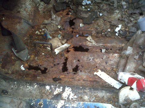 1973 Ford Ranchero - Extensive rust and damage to the interior floor pan of a vehicle, obscuring any specific year identification.