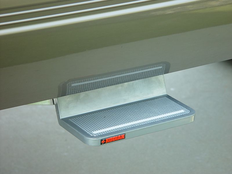 Aluminum Kodiak retractable side step under tan SUV rocker panel