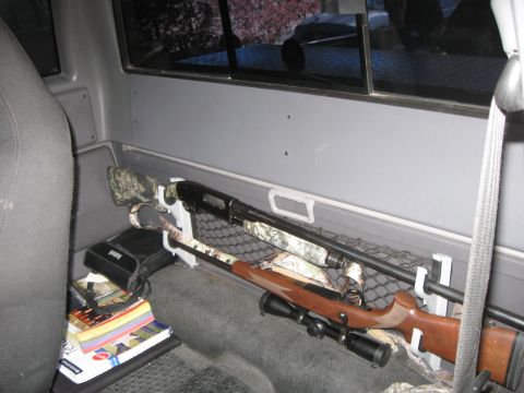 2003 Ford Ranger - Interior view of a pickup truck bed showing two rifles secured for transport.