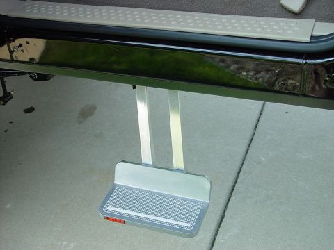 2001 Ford Excursion - A close-up view shows a retractable running board step extended from the side of a dark-colored vehicle.