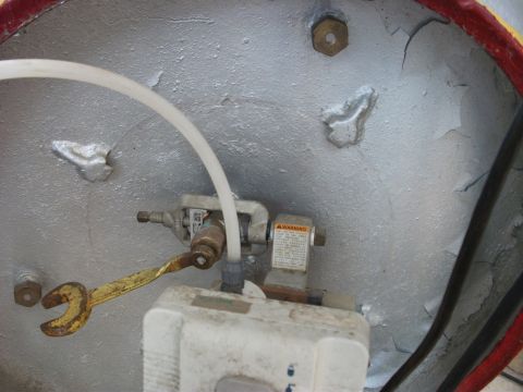 1992 Ford F-150 - Internal view of a tank showing plumbing components and a yellow wrench, with a warning label visible.