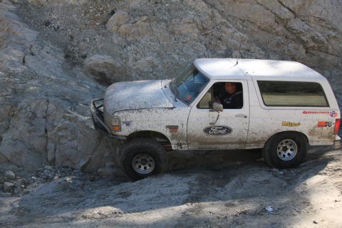 1995 Ford Bronco - A white Ford Bronco navigates a challenging, rocky off-road trail.