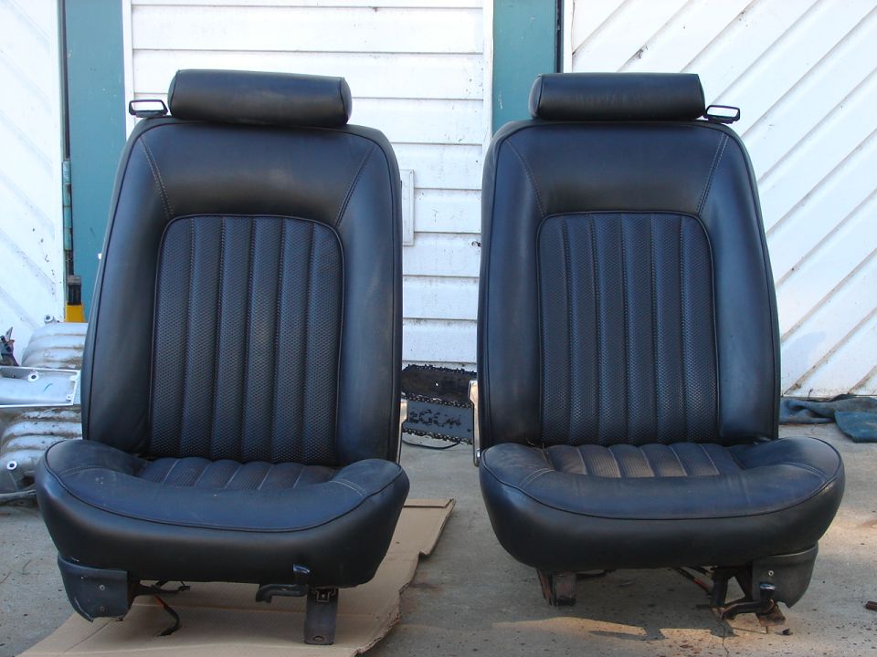 Two black leather car seats with headrests and ribbed seatbacks, viewed from the front