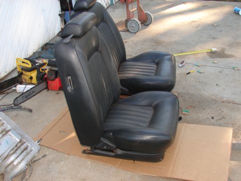 1973 Ford Ranchero - A pair of black leather bucket seats are shown outdoors, with a chainsaw and other tools nearby.