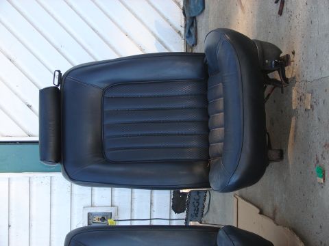 1973 Ford Ranchero - A black car seat is shown outdoors, resting on a concrete surface next to a white wall.