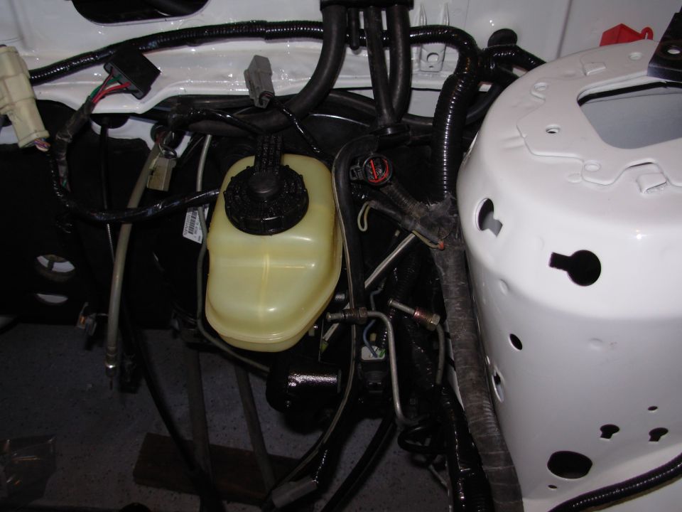 Close-up of a car's brake fluid reservoir and associated wiring in the engine bay