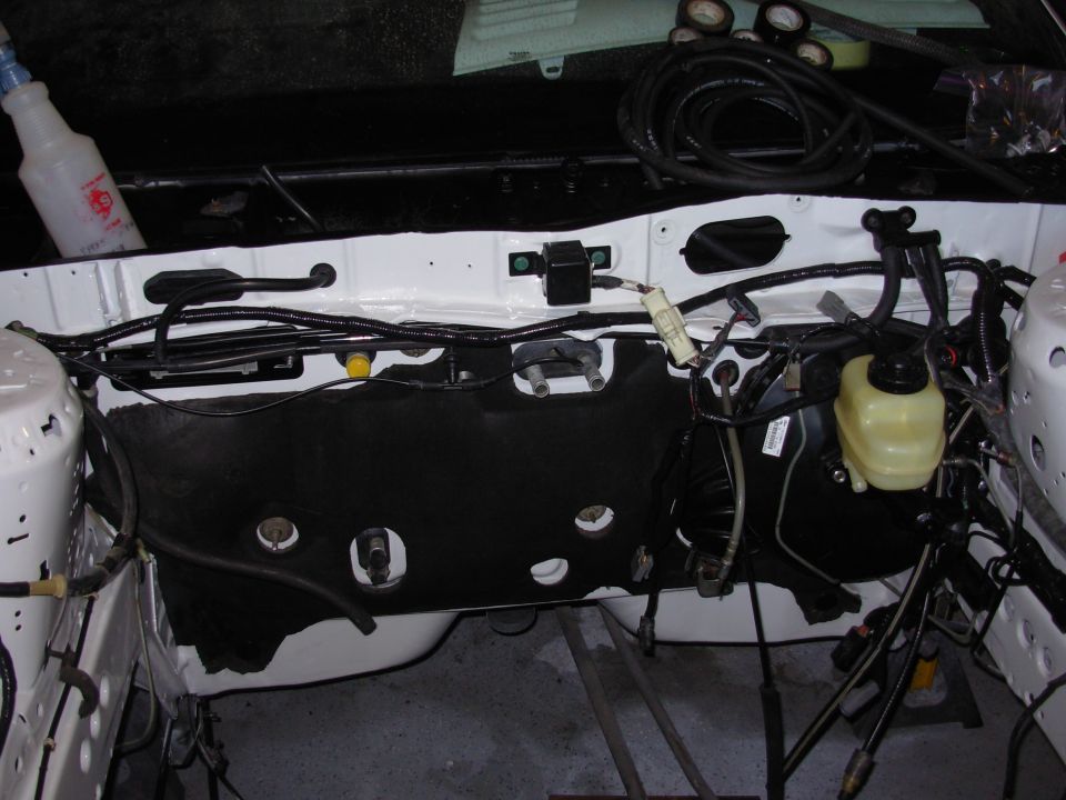 Engine bay with wiring harness, brake fluid reservoir, and black insulation panel