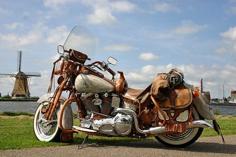 1973 Ford Ranchero - A custom motorcycle with extensive leatherwork and saddlebags is parked outdoors with a windmill in the background.