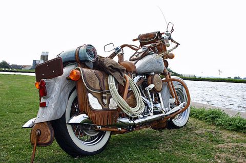 1973 Ford Ranchero - Motorcycle with extensive leather detailing and travel gear parked outdoors near water.