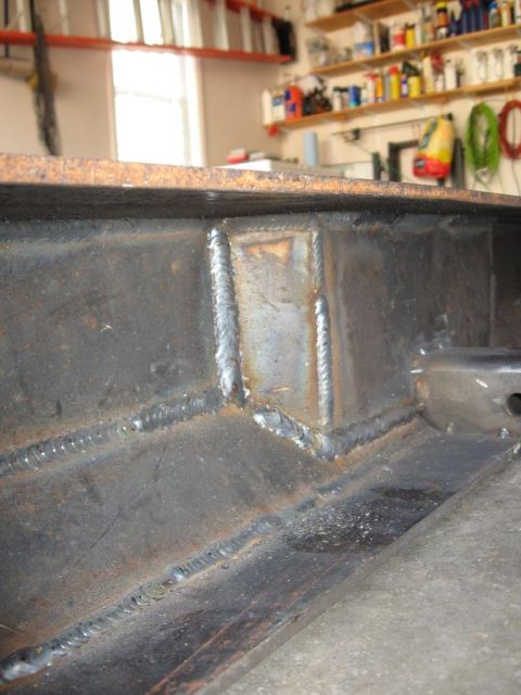 1995 Ford F-150 - Close-up of a heavily welded metal frame, likely part of a vehicle chassis, with visible rust and imperfections.