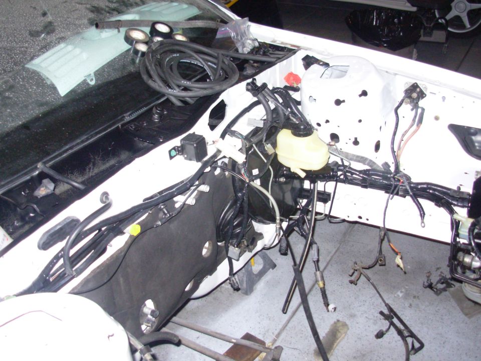 Car's engine bay with wiring harness removed, showing the firewall and brake booster
