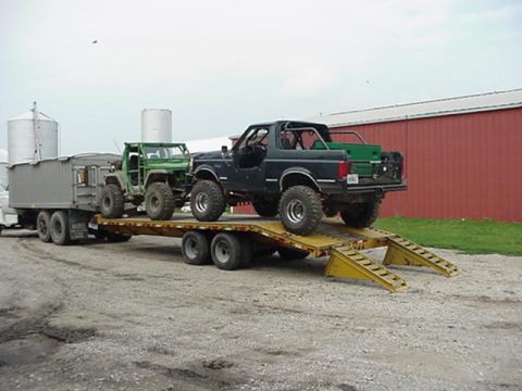 1992 Ford Bronco - A 1992 Ford Bronco and a green Jeep are being transported on a flatbed trailer.
