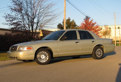 2004 Ford Crown Victoria - Side profile of a gold 2004 Ford Crown Victoria sedan on a sunny day.