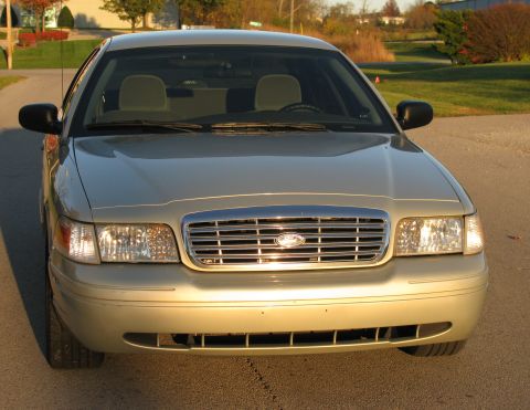 2004 Ford Crown Victoria - The front grille and headlights of a gold 2004 Ford Crown Victoria are visible in this frontal view.