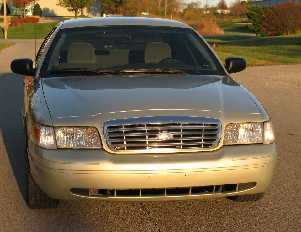 Front view of a gold Ford Crown Victoria with chrome bar grille and Ford oval