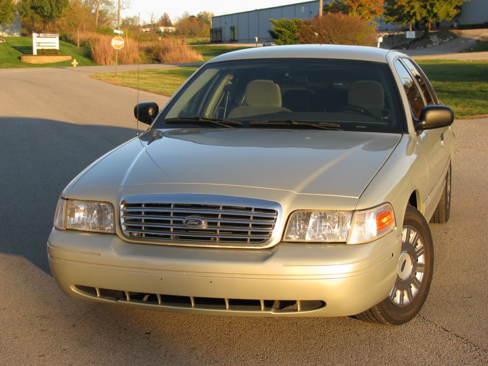 Gold Ford Crown Victoria front 3/4 view with chrome grille and Ford oval badge