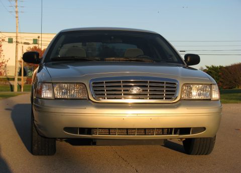 2004 Ford Crown Victoria - The front grille and headlights of a gold 2004 Ford Crown Victoria are visible in this straight-on shot.