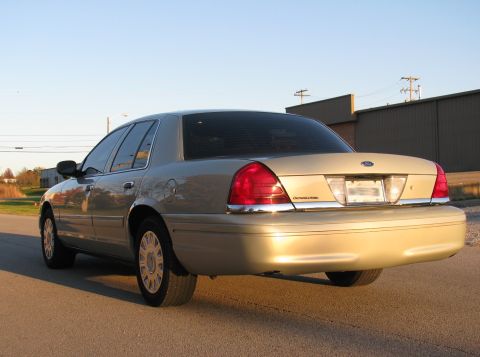 2004 Ford Crown Victoria - Rear 3/4 view of a gold 2004 Ford Crown Victoria parked on a street.