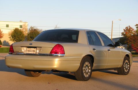 2004 Ford Crown Victoria - Rear 3/4 view of a tan 2004 Ford Crown Victoria parked outdoors.
