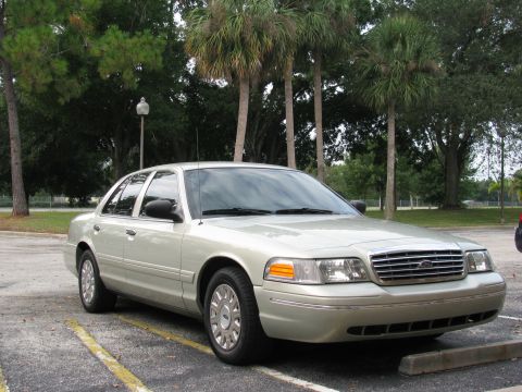 2004 Ford Crown Victoria - A silver 2004 Ford Crown Victoria is parked in a lot with palm trees in the background.