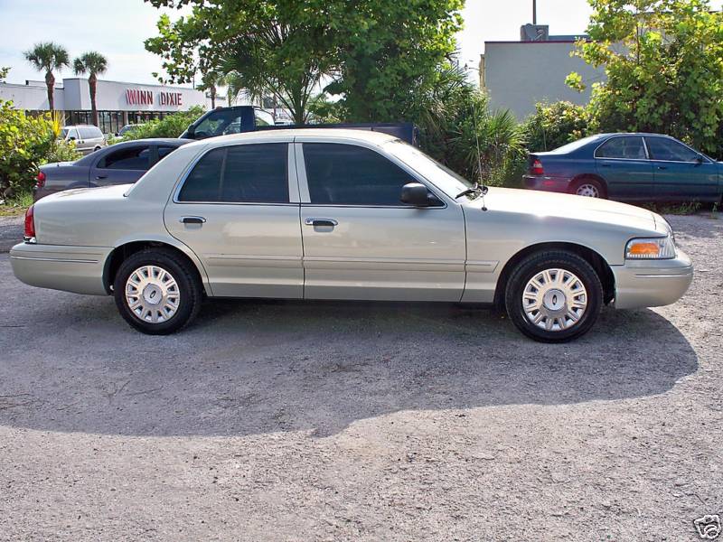 Champagne gold Ford Crown Victoria sedan side profile in front of Winn-Dixie store