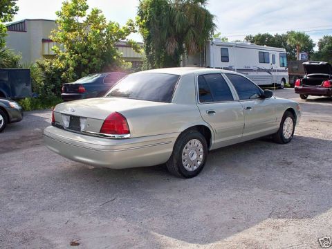 2004 Ford Crown Victoria - A silver Ford Crown Victoria is parked on a gravel lot with other vehicles and an RV visible.