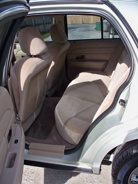 2004 Ford Crown Victoria - Rear interior view of a 2004 Ford Crown Victoria, highlighting the tan upholstery and door trim.