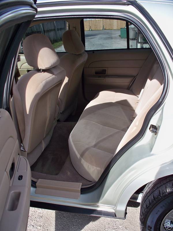 Tan cloth rear bench seat of Ford Crown Victoria through open rear door