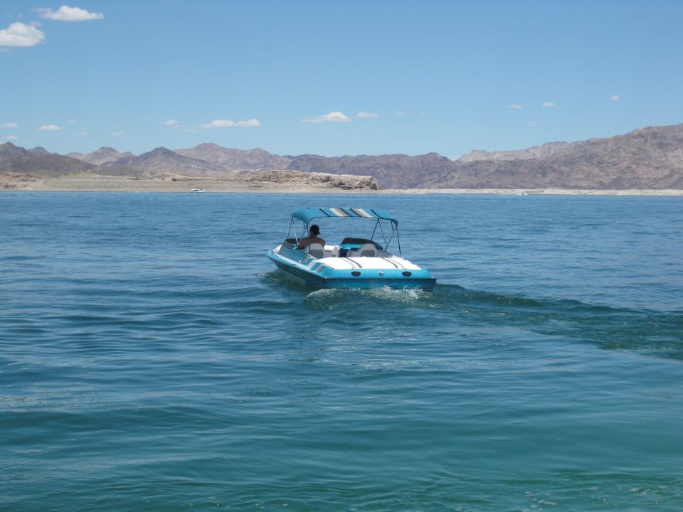 Blue and white boat with a striped canopy on a lake, seen from behind