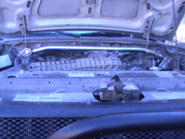 engine bay with hood open, showing engine components and a strut bar
