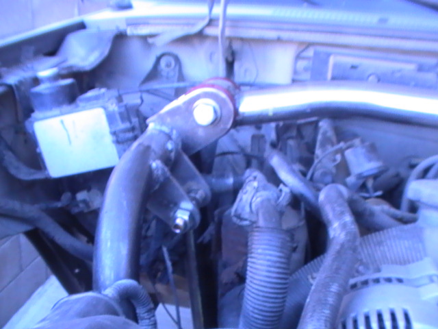 Engine bay with custom exhaust pipe and red bushing