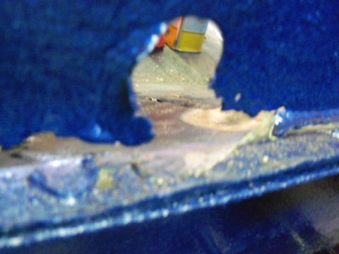 1978 Jeep CJ5 - Blue metal part with a hole, showing rust and damage. Another object is visible through the opening.