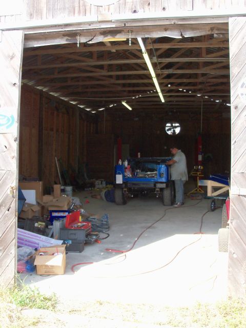 1978 Jeep CJ5 - A blue 1978 Jeep CJ5 is being worked on inside a cluttered garage.