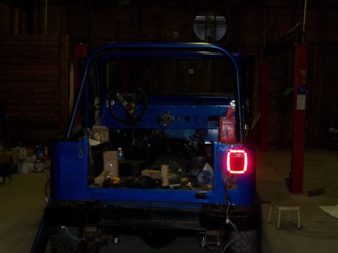 1978 Jeep CJ5 - A blue Jeep CJ is parked inside a garage, showing its rear end and interior.