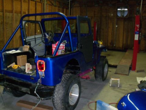 1978 Jeep CJ5 - A blue Jeep CJ5 is parked inside a garage, showing its interior and rear cargo area with the doors open.