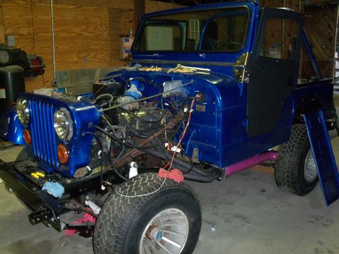 1978 Jeep CJ5 - A blue Jeep CJ is shown in a garage with its hood open, revealing the engine compartment.