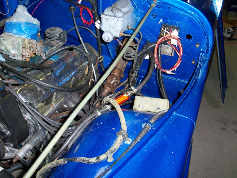 Blue Jeep engine bay with visible carburetor and wiring