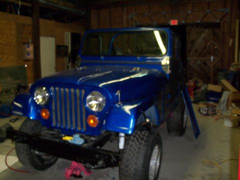 1978 Jeep CJ5 - A blue Jeep CJ is parked inside a garage with its front end facing the camera.