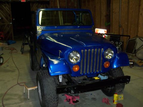 1978 Jeep CJ5 - Front view of a blue 1978 Jeep CJ5 in a garage, showing its iconic vertical grille and round headlights.