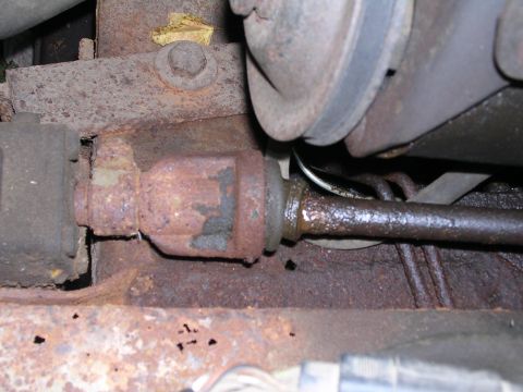 1978 Ford Bronco - Close-up view of a heavily rusted steering linkage, showing signs of wear and grease accumulation.