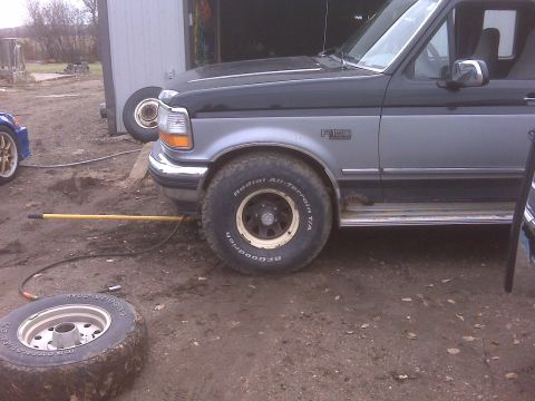 1994 Ford F-150 - A two-tone Ford F-150 pickup truck is parked outside a garage with a spare tire on the ground.