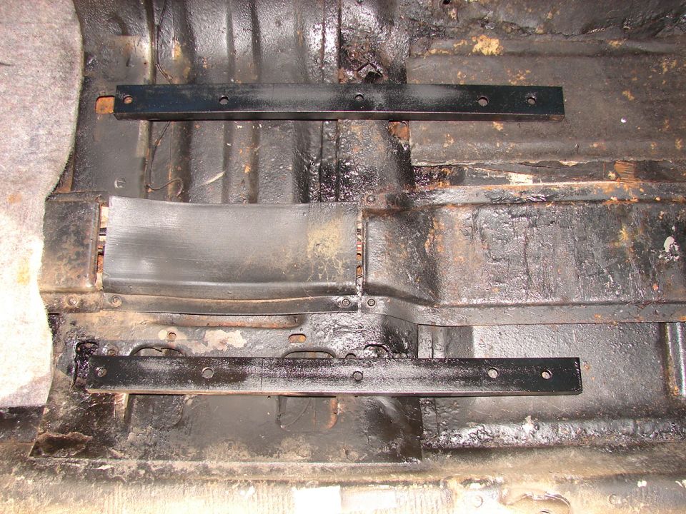 Vehicle floor with black seat mounting rails and rust