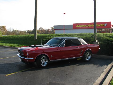 1966 Ford Mustang - Red 1966 Ford Mustang coupe with a black vinyl top and hood scoop is parked outside.