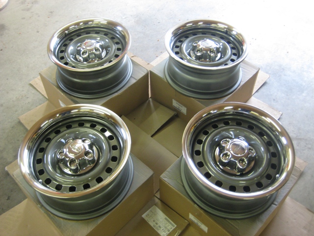 Four steel wheels with chrome trim rings, each sitting on a cardboard box