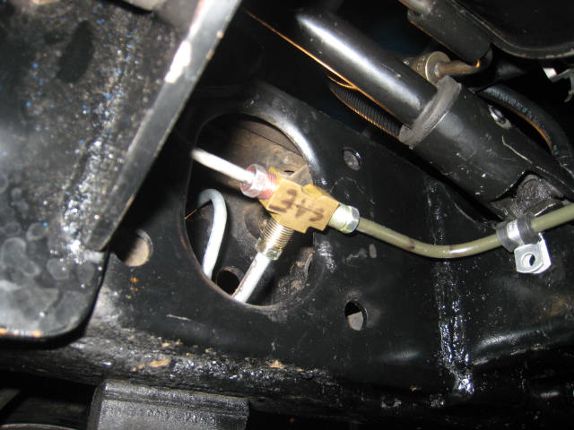 Brake line junction block with a numbered tag underneath a vehicle